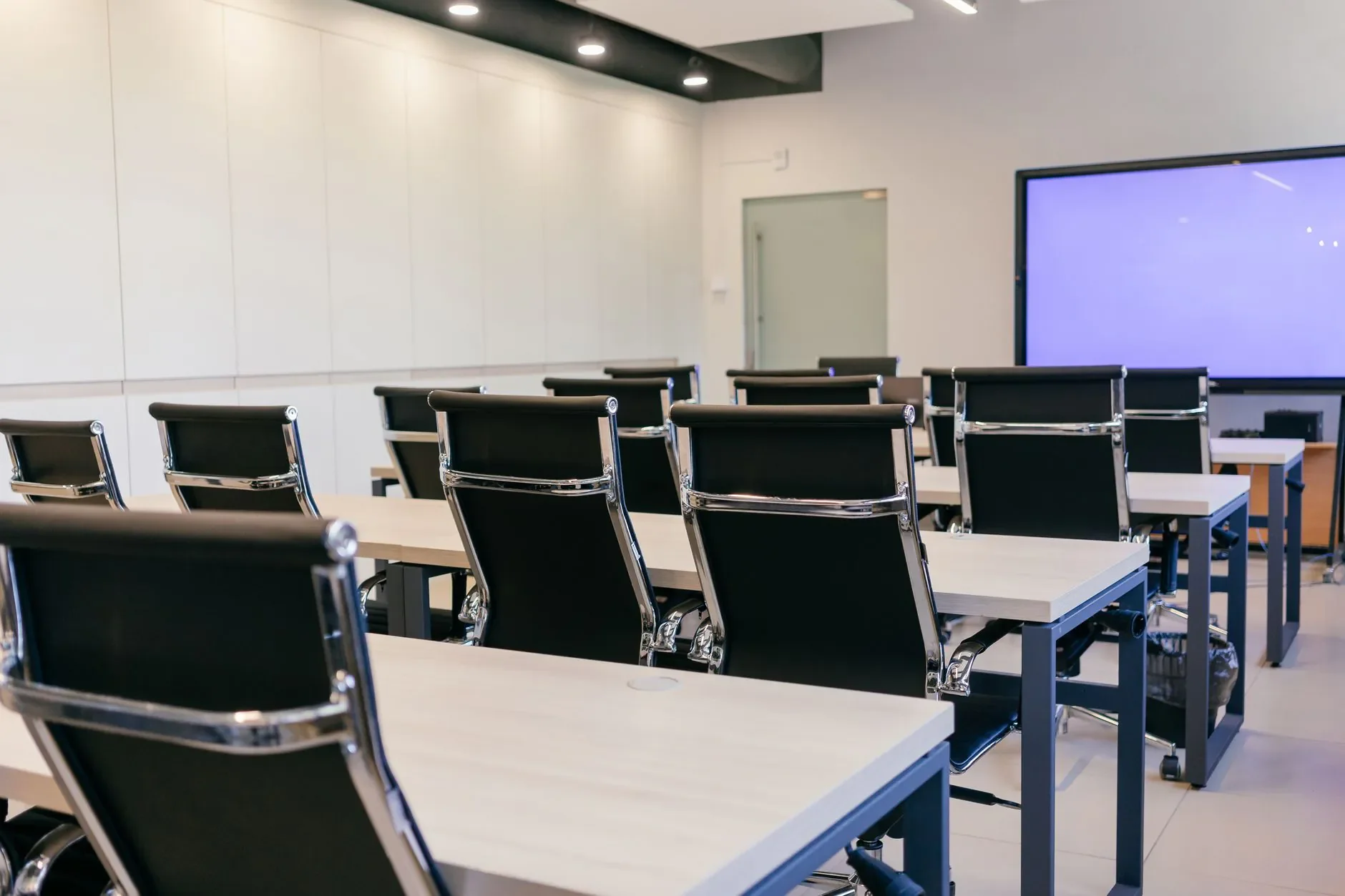 Louer du mobilier événementiel professionnel à Paris Salle de conférence spacieuse et moderne avec des chaises noires et un écran de projection.